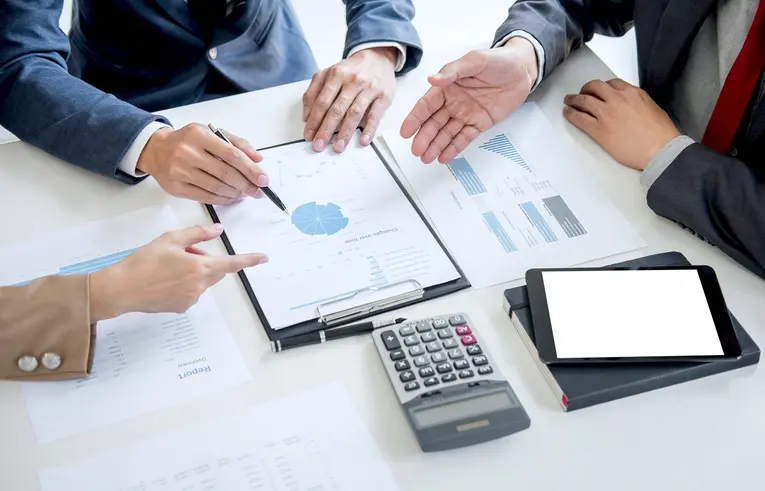 Three people sitting at a table analysing a printed graph