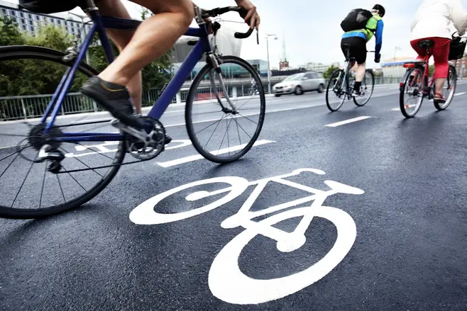 Ścieżka rowerowa w mieście i jadący rowerzyci